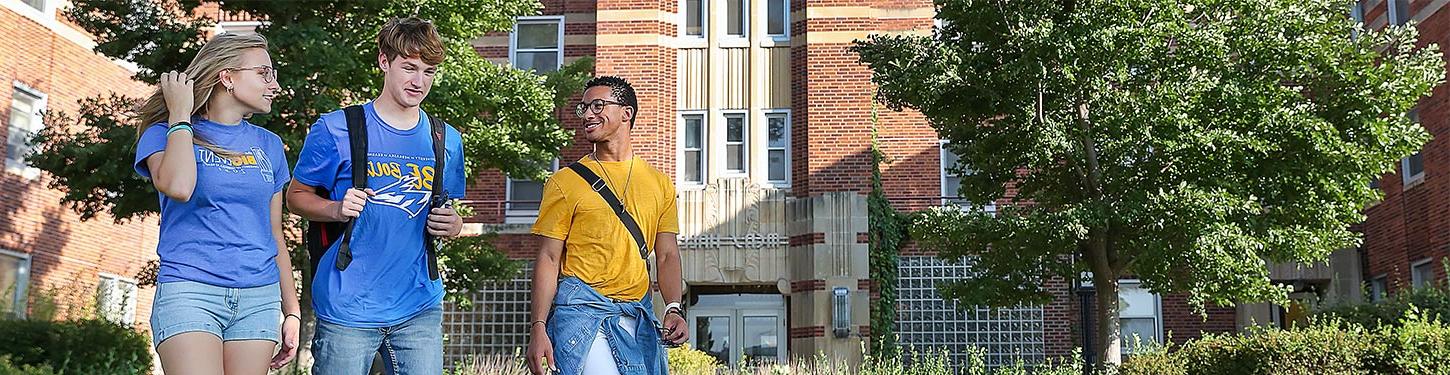 students walk across campus on a sunny afternoon